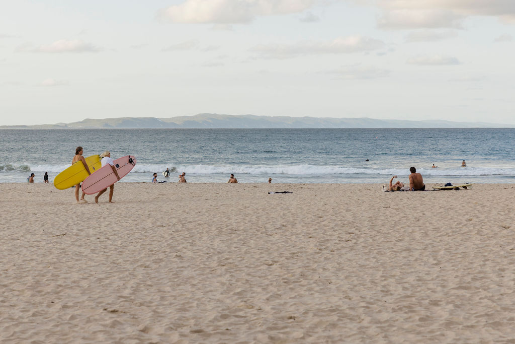 Two surfers walking on Noosa Main Beach towards the water